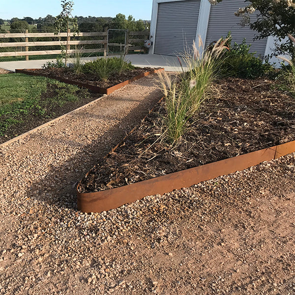 Rusted corten steel garden edging installed along gravel garden pathway